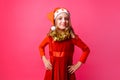 Cute teen in Santa hat and with tinsel on neck smiling on red ba Royalty Free Stock Photo