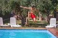 Excited teenager in jumping action into a serene summer pool Royalty Free Stock Photo