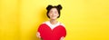 Cute teenage asian girl dreaming of true love, close eyes and showing big red heart cutout, waiting for soulmate on Royalty Free Stock Photo