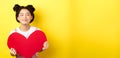 Cute teenage asian girl dreaming of true love, close eyes and showing big red heart cutout, waiting for soulmate on Royalty Free Stock Photo
