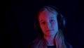 Cute teenage girl in headphones listening music in darkness