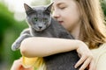 Cute teenage girl holding her pet cat on sunny summer day. Gorgeous grey Russian Blue breed cat outdoors Royalty Free Stock Photo