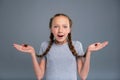 Cute teenage girl holding two braids and shrugging