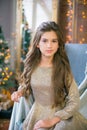 A cute teenage girl with long curly hair in a shining dress in a room decorated for Christmas with shining garlands Royalty Free Stock Photo