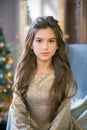 A cute teenage girl with long curly hair in a shining dress in a room decorated for Christmas with shining garlands Royalty Free Stock Photo