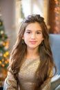 A cute teenage girl with long curly hair in a shining dress in a room decorated for Christmas with shining garlands Royalty Free Stock Photo