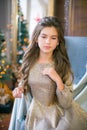 A cute teenage girl with long curly hair in a shining dress in a room decorated for Christmas with shining garlands Royalty Free Stock Photo