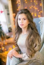 A cute teenage girl with long curly hair in a shining dress in a room decorated for Christmas with shining garlands Royalty Free Stock Photo