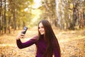 Cute girl with a smartphone in the autumn forest.