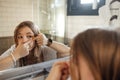 Cute teenage girl squeezes out a pimple on her cheek in the bathroom