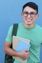 Cute teenager boy in formal high school uniform holding notebooks smiling wearing glasses and backpack