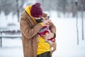 Cute teenager holding french bulldog puppy in his hands and kissing it outdoor on a snow background. Royalty Free Stock Photo