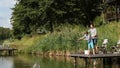 Cute teenager learning to fish on lake in summer