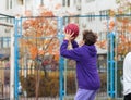 Cute teenager in violet hoodie playing basketball. Young boy with ball learning dribble and shooting on the city court. Hobby Royalty Free Stock Photo