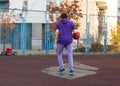 Cute teenager in violet hoodie playing basketball. Young boy with ball learning dribble and shooting on the city court. Hobby Royalty Free Stock Photo