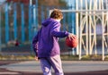 Cute teenager in violet hoodie playing basketball. Young boy with ball learning dribble and shooting on the city court. Hobby Royalty Free Stock Photo