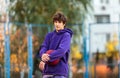 Cute teenager in violet hoodie playing basketball. Young boy with ball learning dribble and shooting on the city court. Hobby Royalty Free Stock Photo