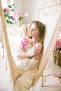 Cute tender young girl with blond hair in white clothes and lace underwear surrounded by pink peonies on the bed Royalty Free Stock Photo