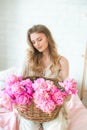 Cute tender young girl with blond hair in white clothes and lace underwear surrounded by pink peonies on the bed Royalty Free Stock Photo