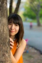 Cute Thai girl hiding behind the tree