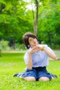 Cute Thai schoolgirl is sitting on the grass and doing heart symbol.