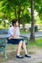 Cute Thai schoolgirl is sitting and studying on a bench Royalty Free Stock Photo