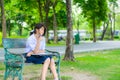 Cute Thai schoolgirl is sitting and studying on a bench Royalty Free Stock Photo