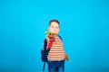 Cute three year old preschooler with a backpack on blue background. For the first time to school. Royalty Free Stock Photo