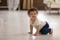 Cute toddler African American girl crawling on warm wooden floor Royalty Free Stock Photo