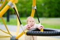 Cute toddler baby having fun on outdoor playground. Adorable little girl is swinging. Kindergarten, daycare, nursery for small Royalty Free Stock Photo