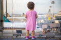 Cute Toddler baby in a pink dress looks at the planes at the airport. Waiting for a flight flight. back view