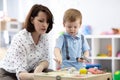 Cute toddler baby playing with busyboard. Mother or babysitter teaching kid in nursery. Children`s educational toys. Royalty Free Stock Photo