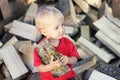 Cute toddler blond boy with aspen log on the pile of firewood background. Country lifestyle