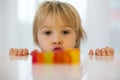 Cute toddler blond boy, looking at colorful gummy bears on the table Royalty Free Stock Photo