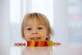 Cute toddler blond boy, looking at colorful gummy bears on the table Royalty Free Stock Photo