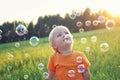 Cute toddler blond boy playing with soap bubbles on summer field. Happy child summertime concept. Authentic lifestyle image Royalty Free Stock Photo