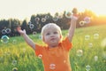 Cute toddler blond boy playing with soap bubbles on summer field. Happy child summertime concept. Authentic lifestyle image Royalty Free Stock Photo