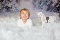 Cute toddler blond boy, playing with white wooden horse in the snow Royalty Free Stock Photo