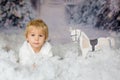 Cute toddler blond boy, playing with white wooden horse in the snow Royalty Free Stock Photo