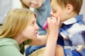 A cute toddler boy is at an appointment with a caring pediatrician. The doctor ENT is examines nose of a little patient using Royalty Free Stock Photo