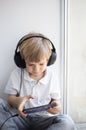 Cute toddler boy in big headphones and a mobile phone, sits alone Royalty Free Stock Photo