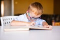 Cute toddler boy with down syndrome with big glasses reading intesting book