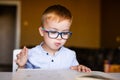 Cute toddler boy with down syndrome with big glasses reading intesting book