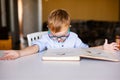 Cute toddler boy with down syndrome with big glasses reading intesting book