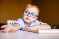 Cute toddler boy with down syndrome with big glasses reading intesting book