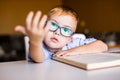 Cute toddler boy with down syndrome with big glasses reading intesting book