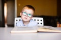 Cute toddler boy with down syndrome with big glasses reading intesting book