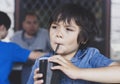 Cute toddler boy drinking cold drink, Happy Child sitting in cafe drinking soda or soft drink with a straw, Unhealthy drink for Royalty Free Stock Photo