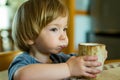 Cute toddler boy drinking decaffeinated coffee at home. Small child drinking hot beverage indoors