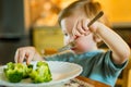 Cute toddler boy eating broccoli. First solid foods. Fresh organic vegetables for infants. Healthy nutrition for the family Royalty Free Stock Photo